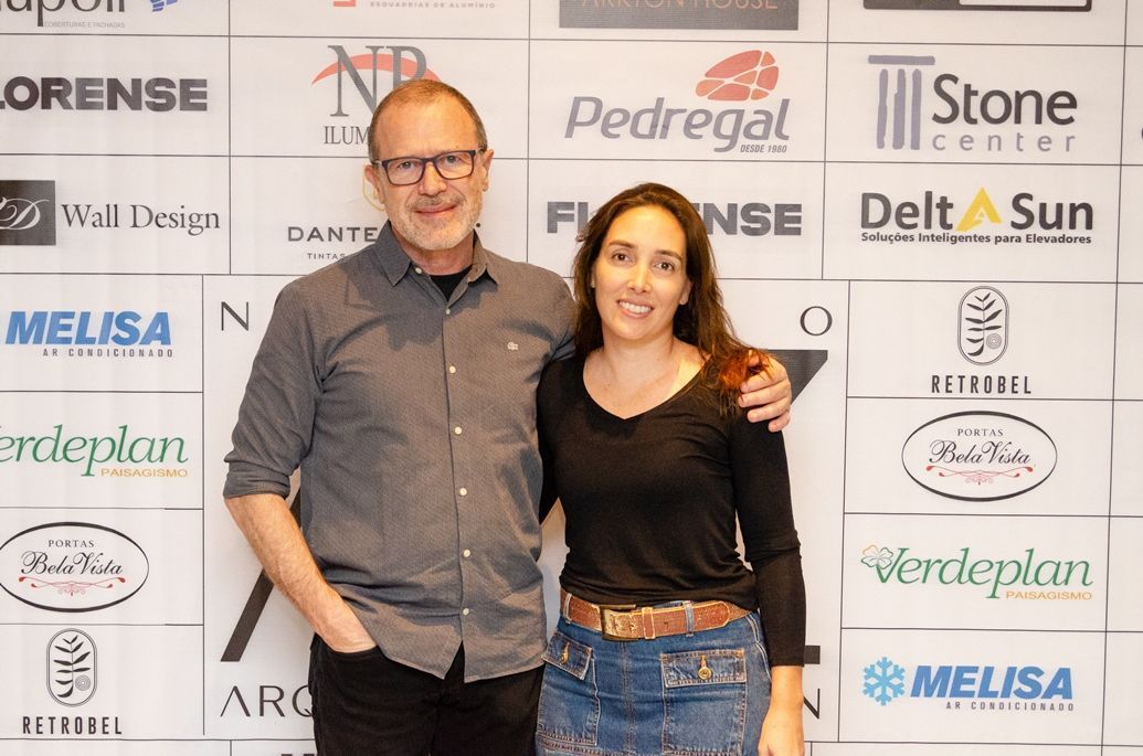 Um homem e uma mulher estão posando para uma foto em frente a uma parede de logotipos.