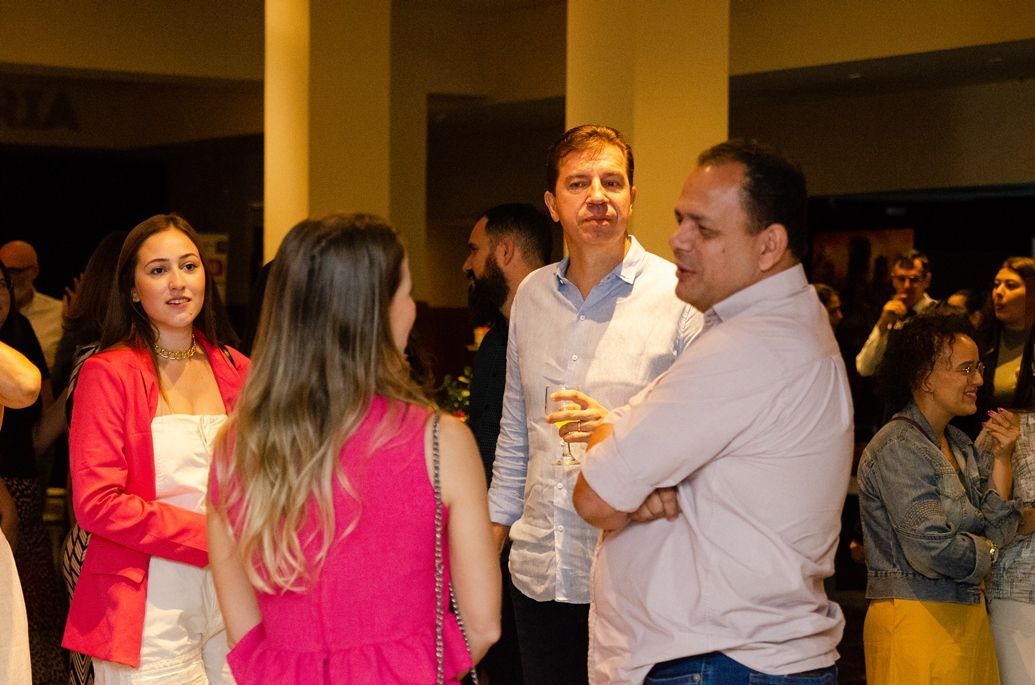 Um grupo de pessoas está em uma sala conversando entre si.