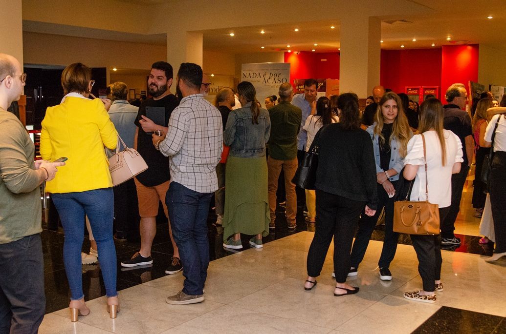 Um grupo de pessoas está em um saguão conversando entre si.