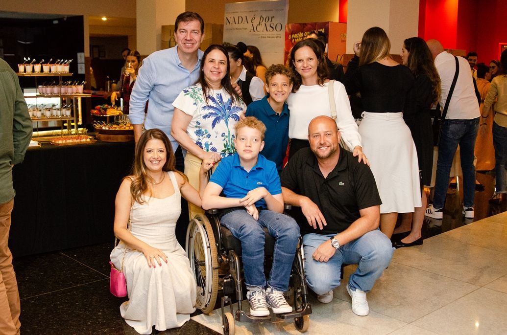 Um grupo de pessoas posando para uma foto com um menino em uma cadeira de rodas.