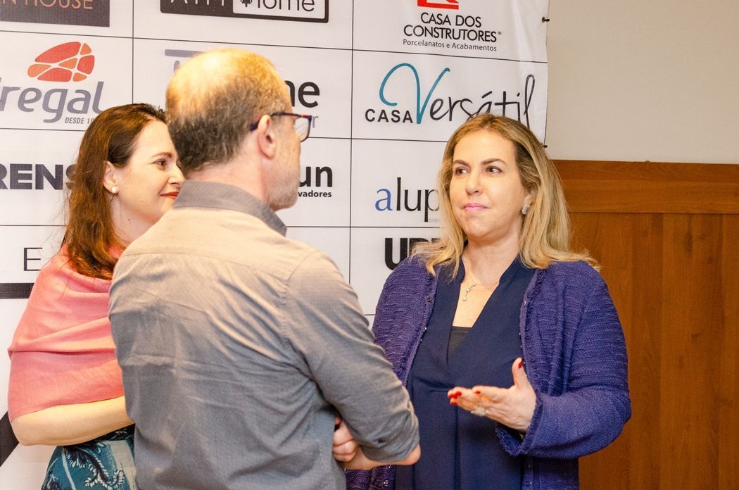 Um grupo de pessoas está em pé em frente a uma parede com logotipos da Regal e da Alup