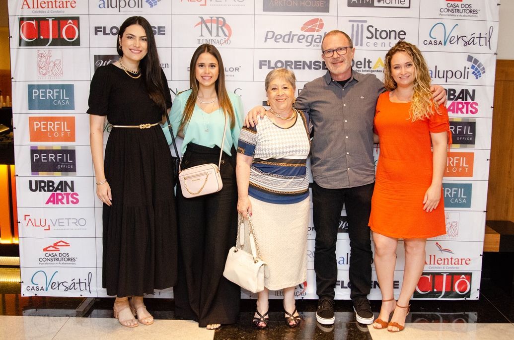 Um grupo de pessoas está posando para uma foto em frente a uma parede com logotipos.