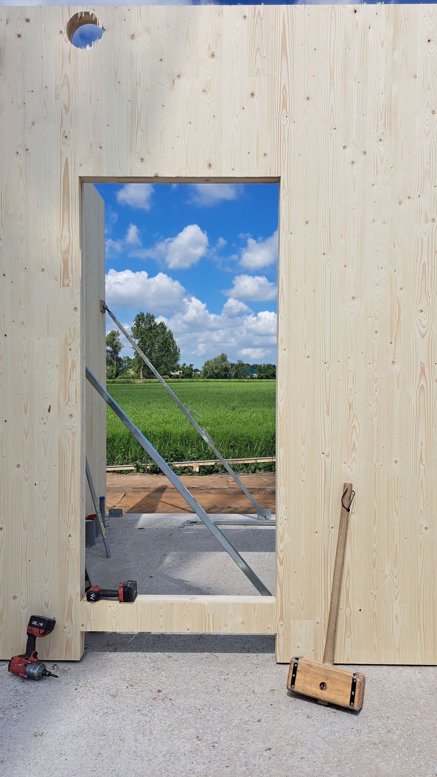 Een raam in een houten wand met uitzicht op een veld.