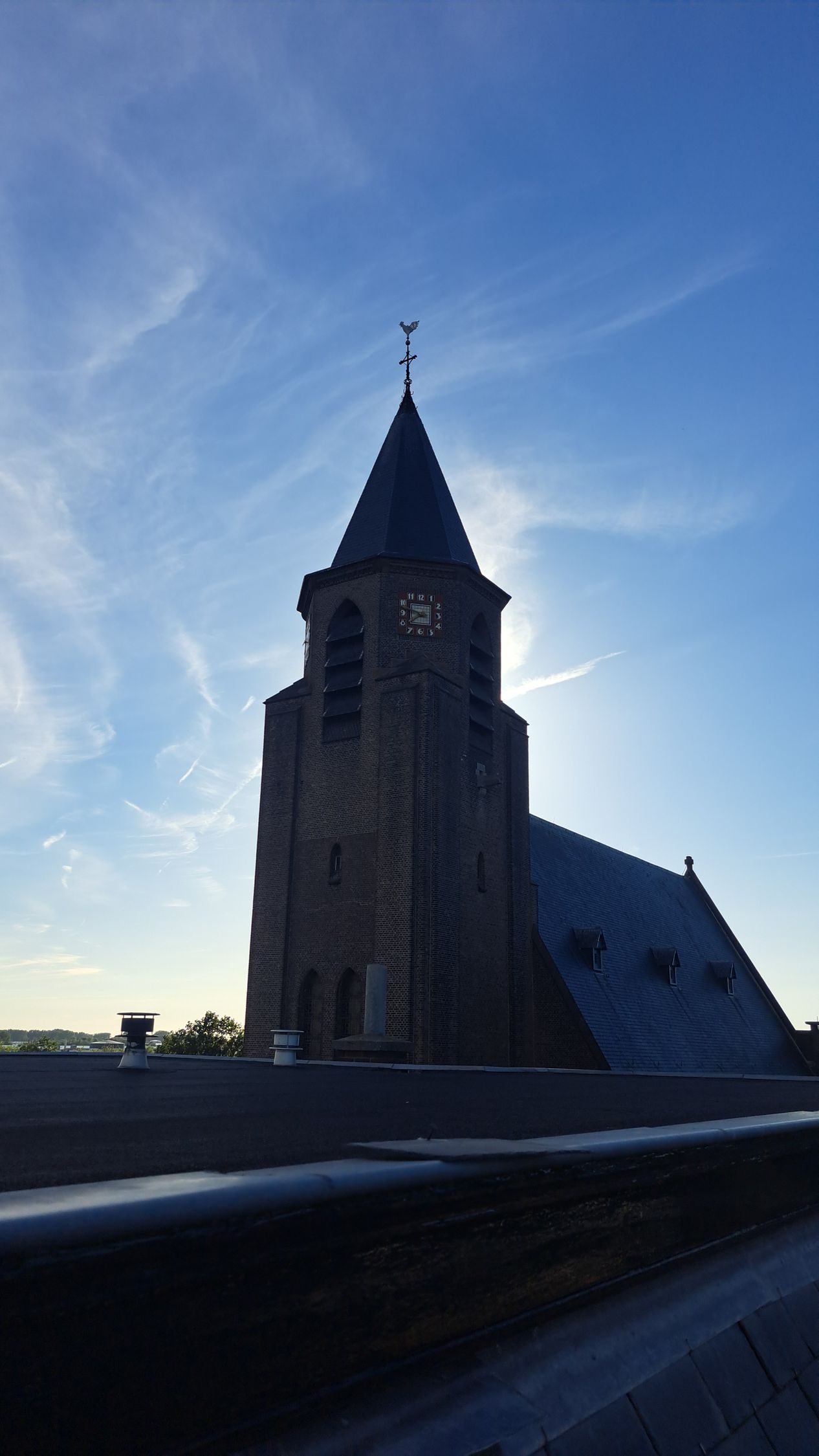 Een kerk met een klokkentoren en een blauwe lucht op de achtergrond.