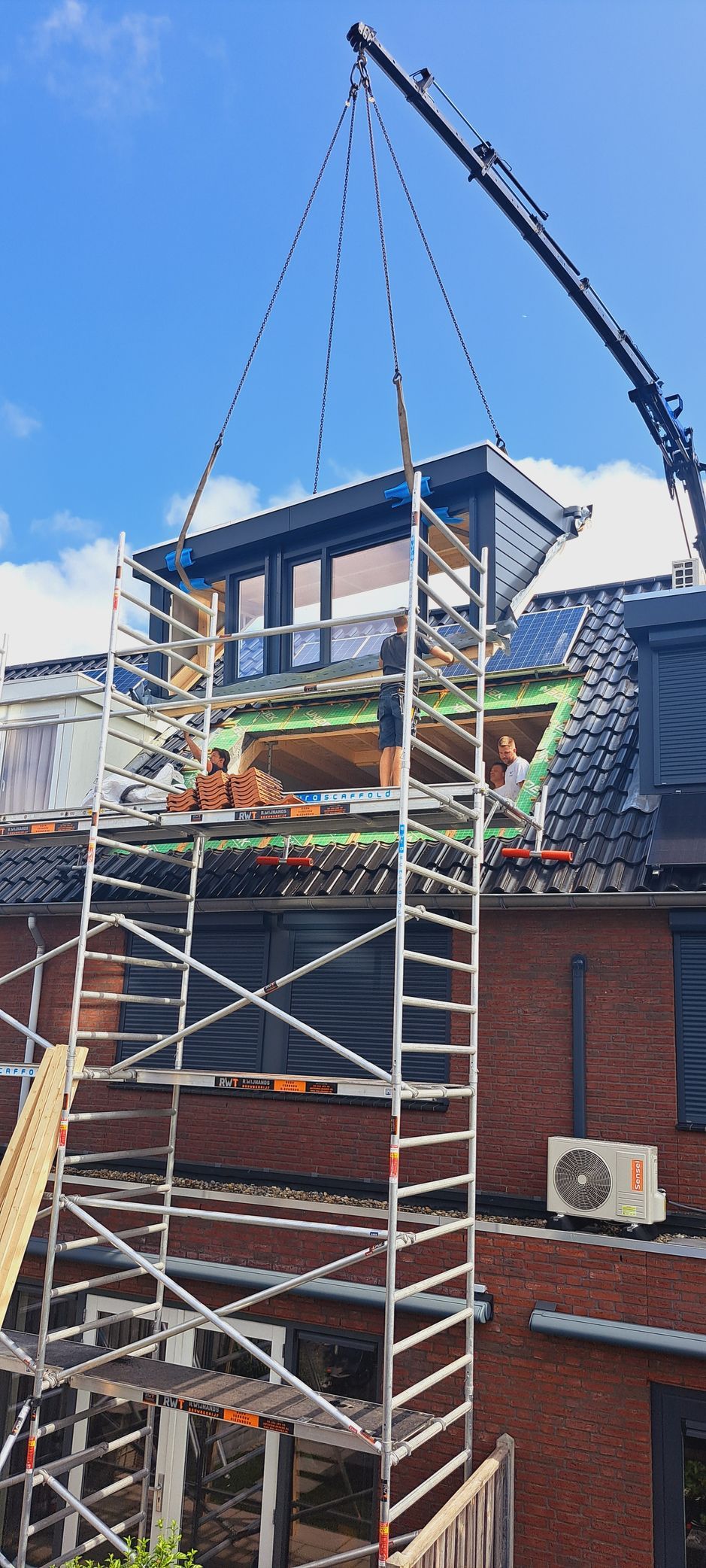 Een man staat op een steiger bovenop een gebouw.