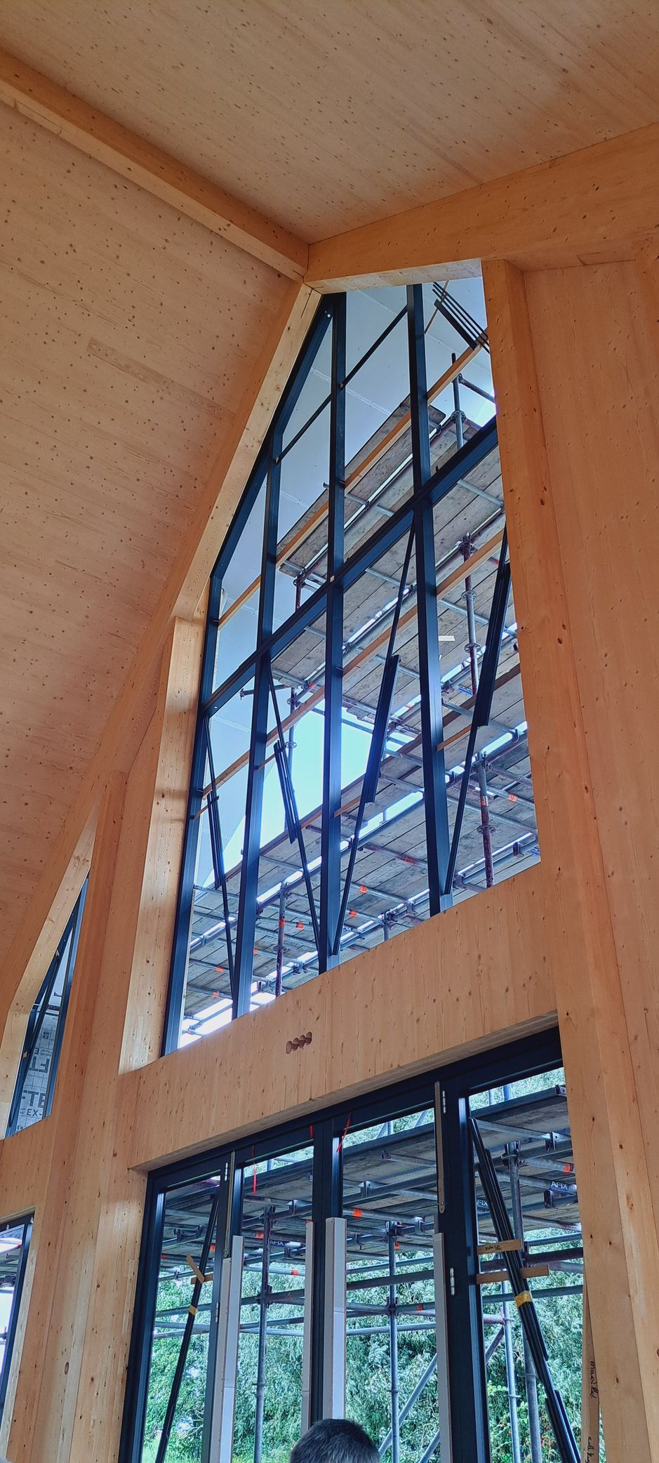 Een man staat voor een groot raam in een gebouw in aanbouw.