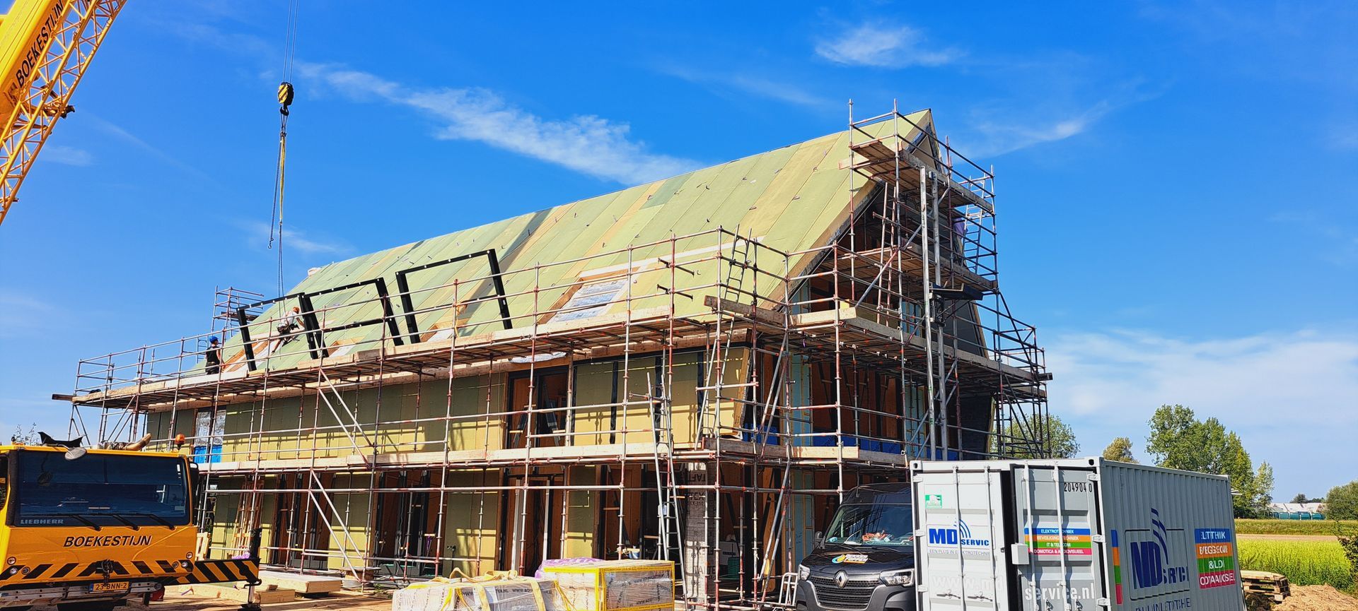Er wordt een huis gebouwd, met op de achtergrond een kraan.