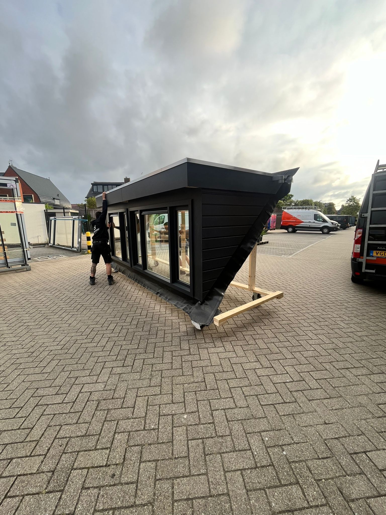 Een man staat naast een groot gebouw op een parkeerplaats.