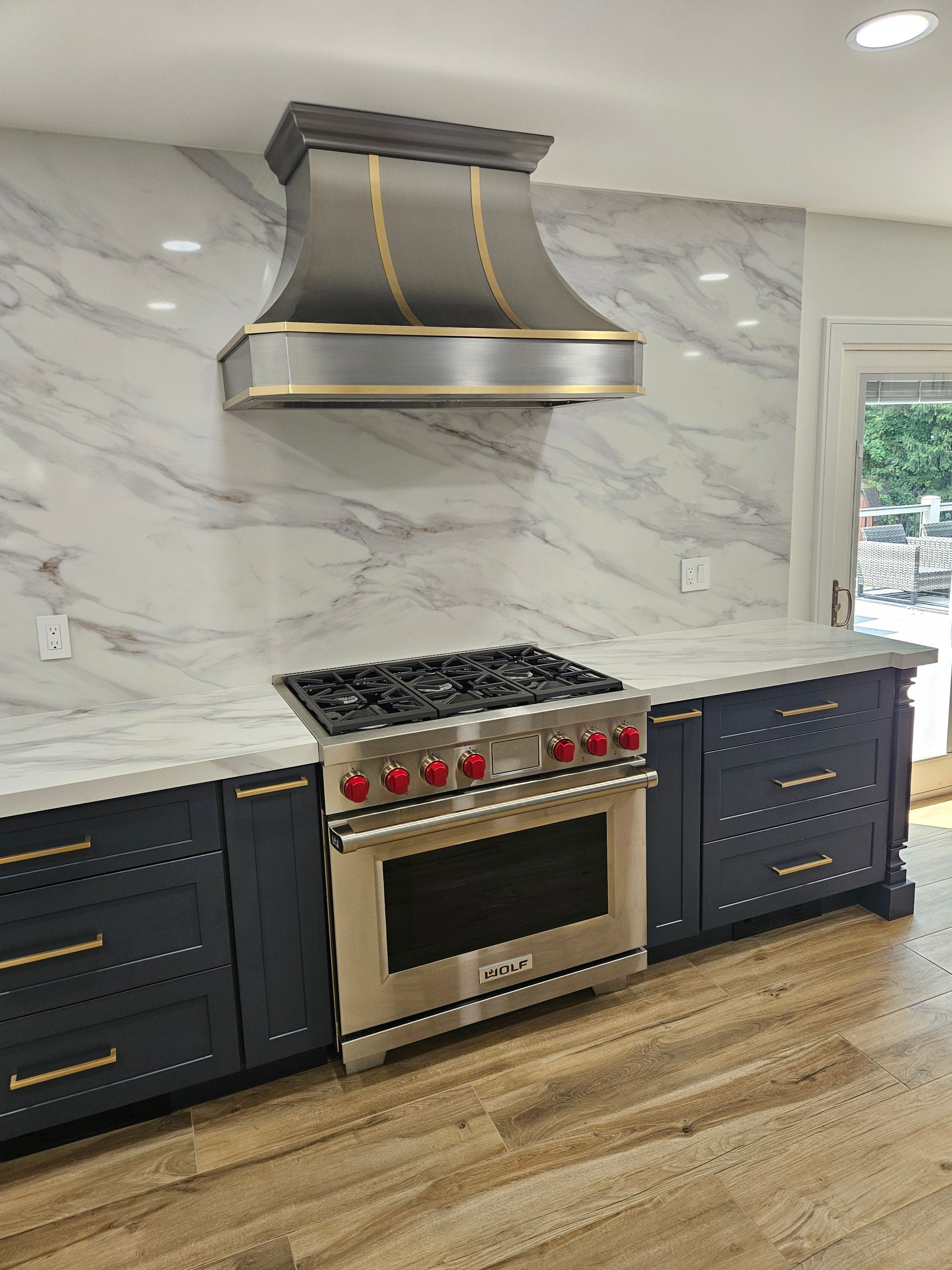 Person in blue gloves fixing a black gas stovetop with a tool.