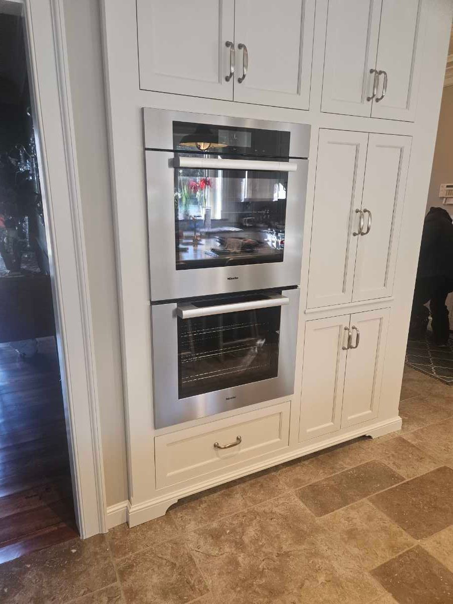 Stainless steel outdoor grill on stone patio with a wooded background.