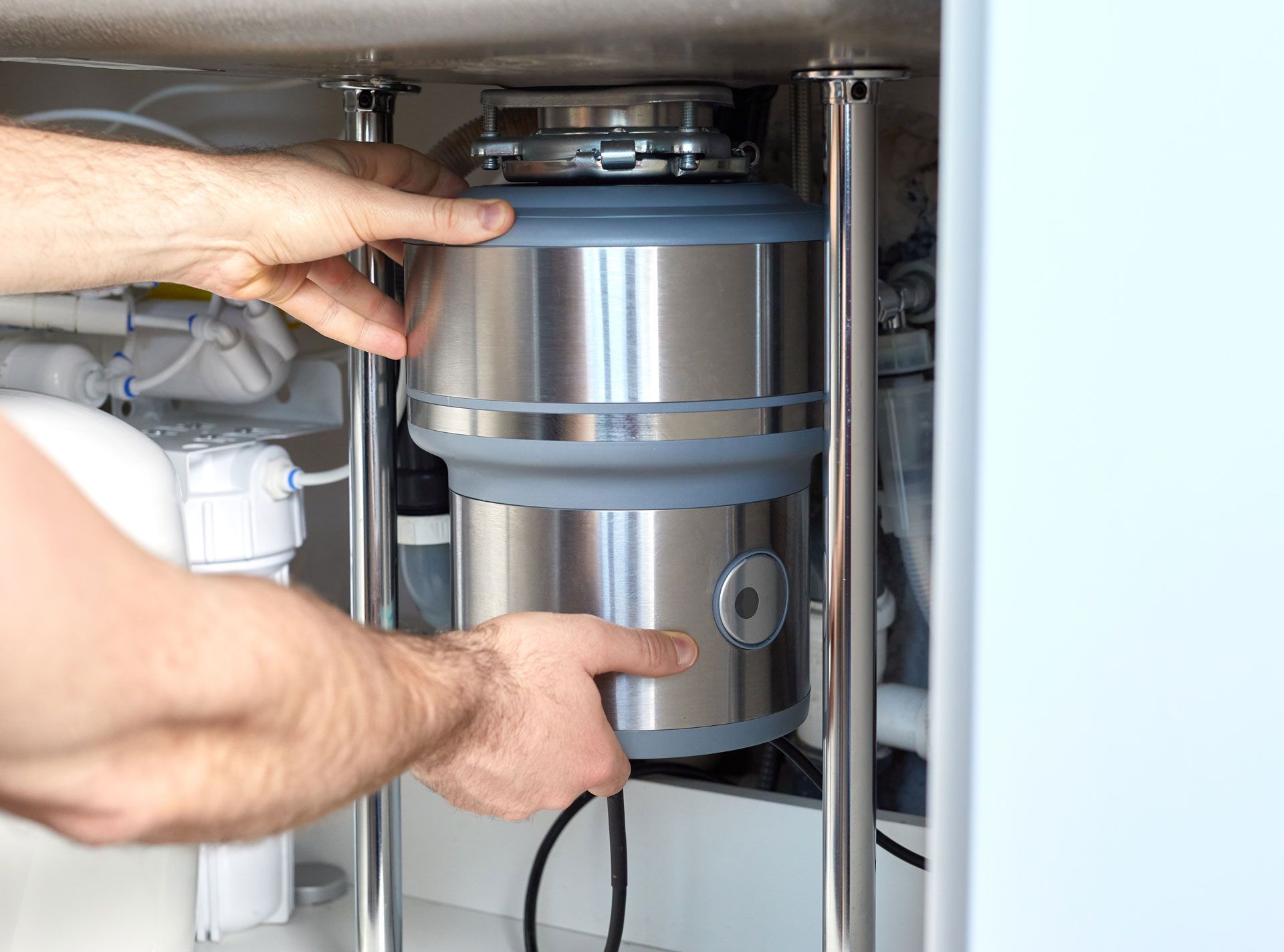Person installing a garbage disposal under a sink.