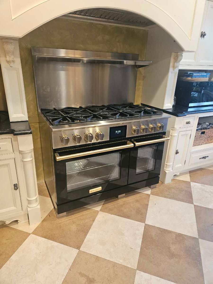 Modern gray kitchen with stainless steel appliances, white countertops, and patterned rug.