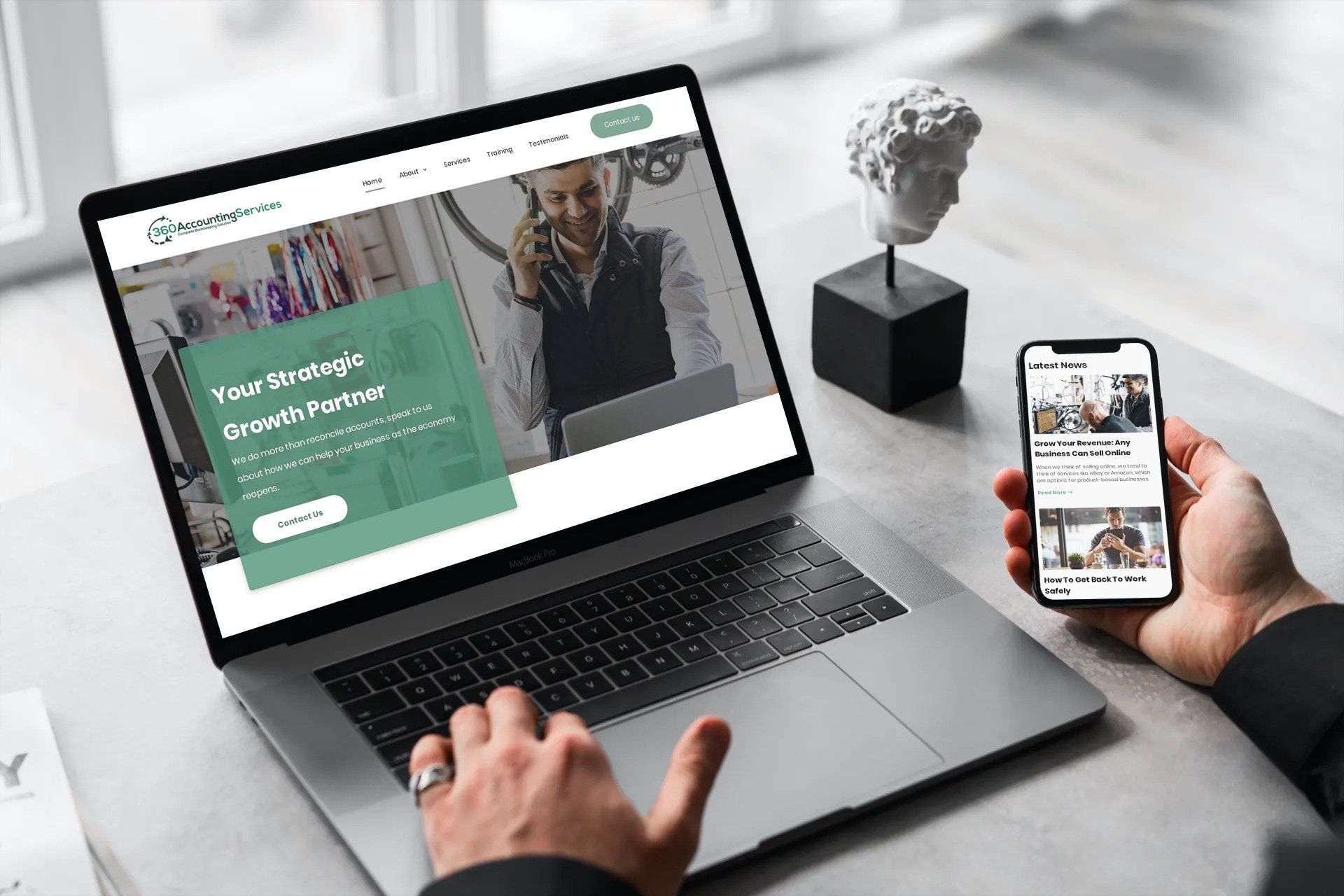 a person is holding a cell phone in front of a laptop computer .