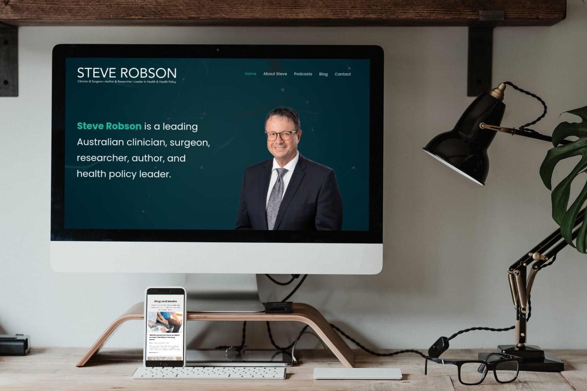 a computer monitor is sitting on a desk next to a lamp and a cell phone .