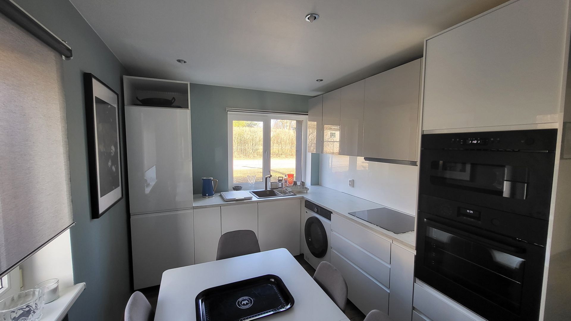 A kitchen with white cabinets , black appliances , a table and chairs.