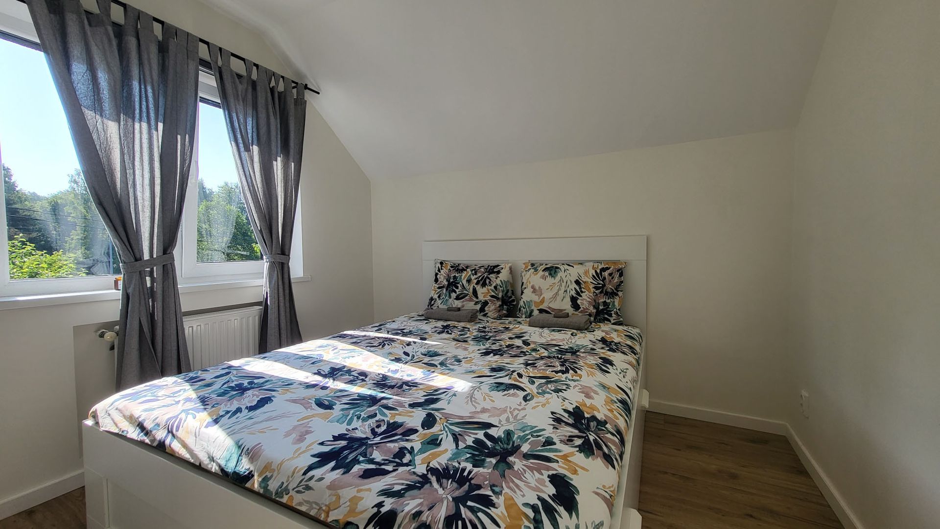 A bedroom with a bed , curtains and a window.