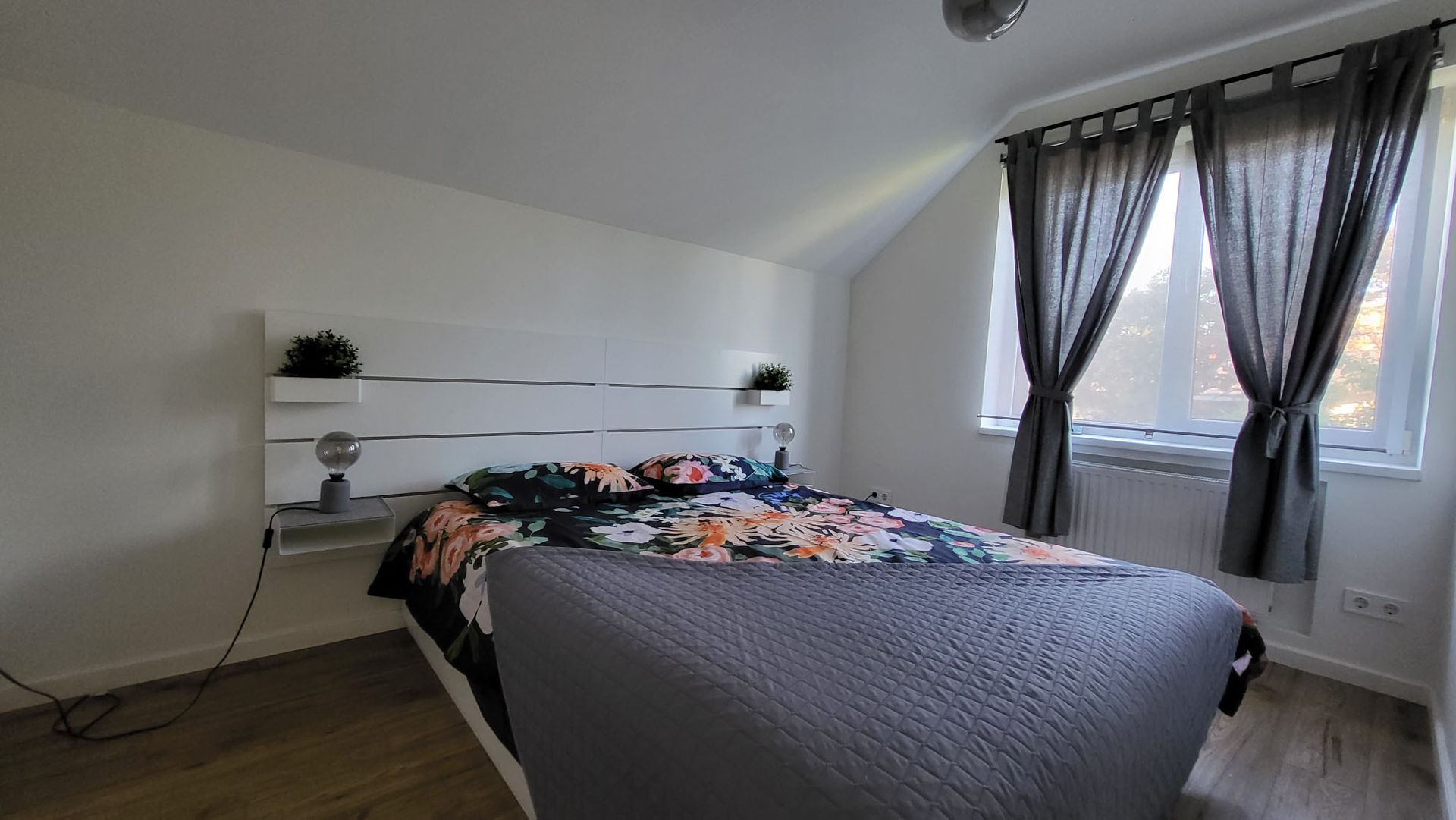 A bedroom with a bed , curtains and a window.