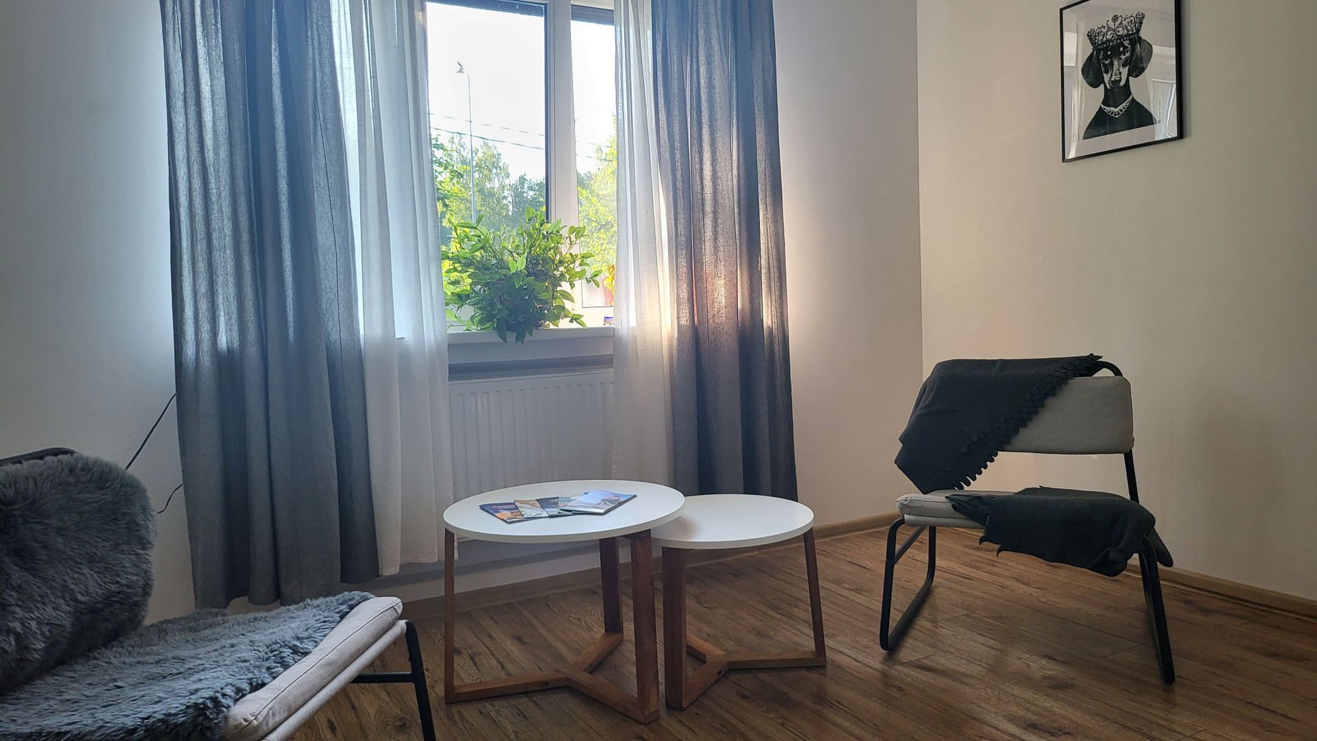 A living room with two tables and a chair in front of a window.