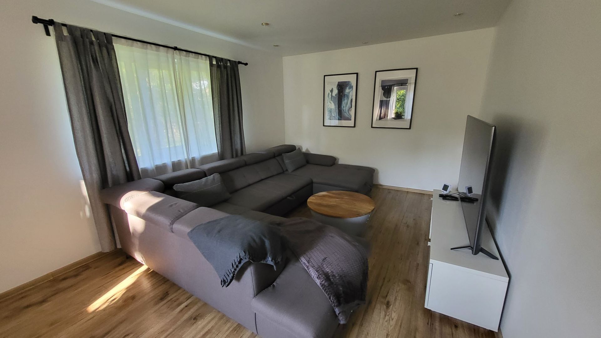 A living room with a large sectional couch and a flat screen tv.