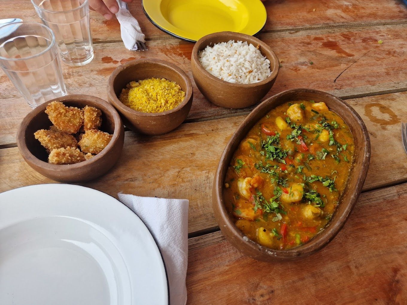 Uma mesa de madeira coberta com tigelas de comida e pratos