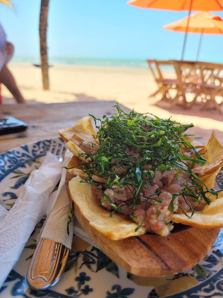 Um close de um prato de comida sobre uma mesa com guarda-chuvas ao fundo.