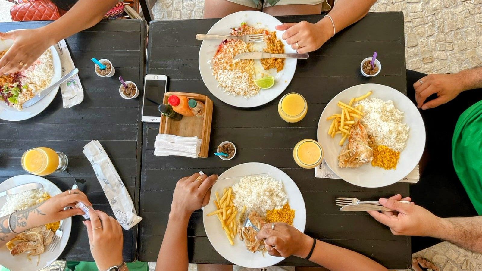 Um grupo de pessoas está sentado em uma mesa comendo.