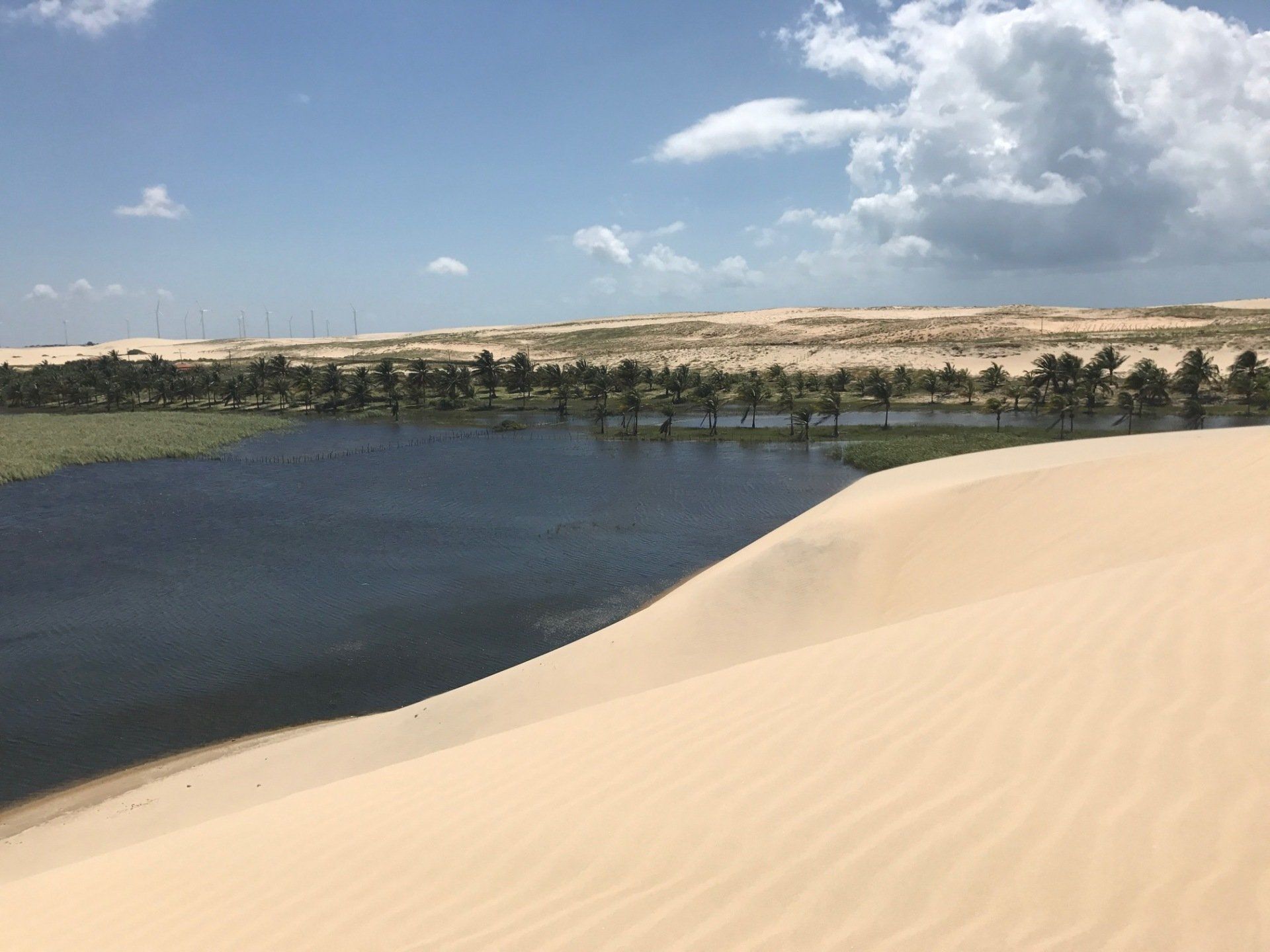 Existe um lago no meio do deserto cercado por dunas de areia.