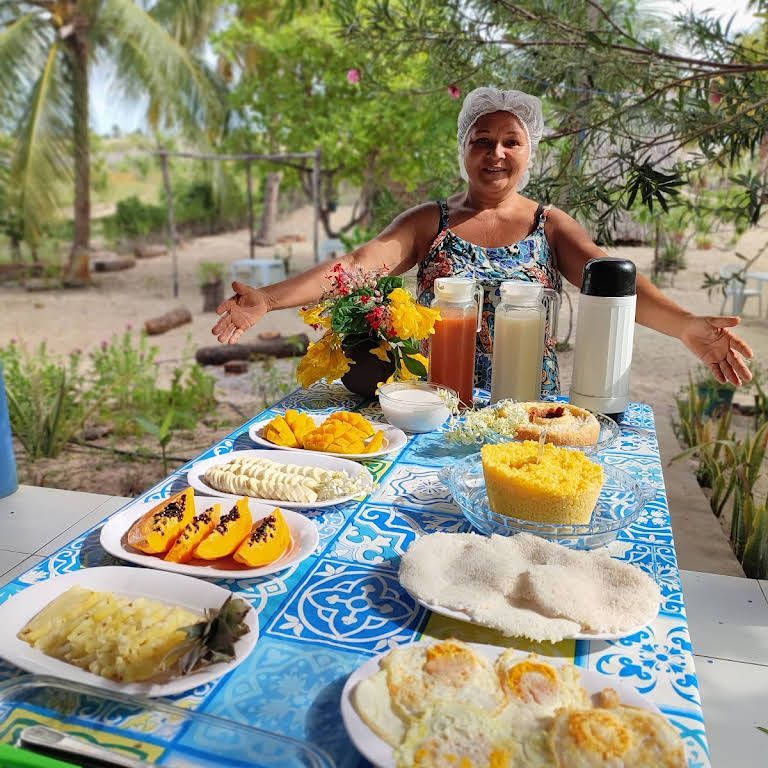 Uma mulher está de pé em uma mesa com pratos de comida sobre ela.