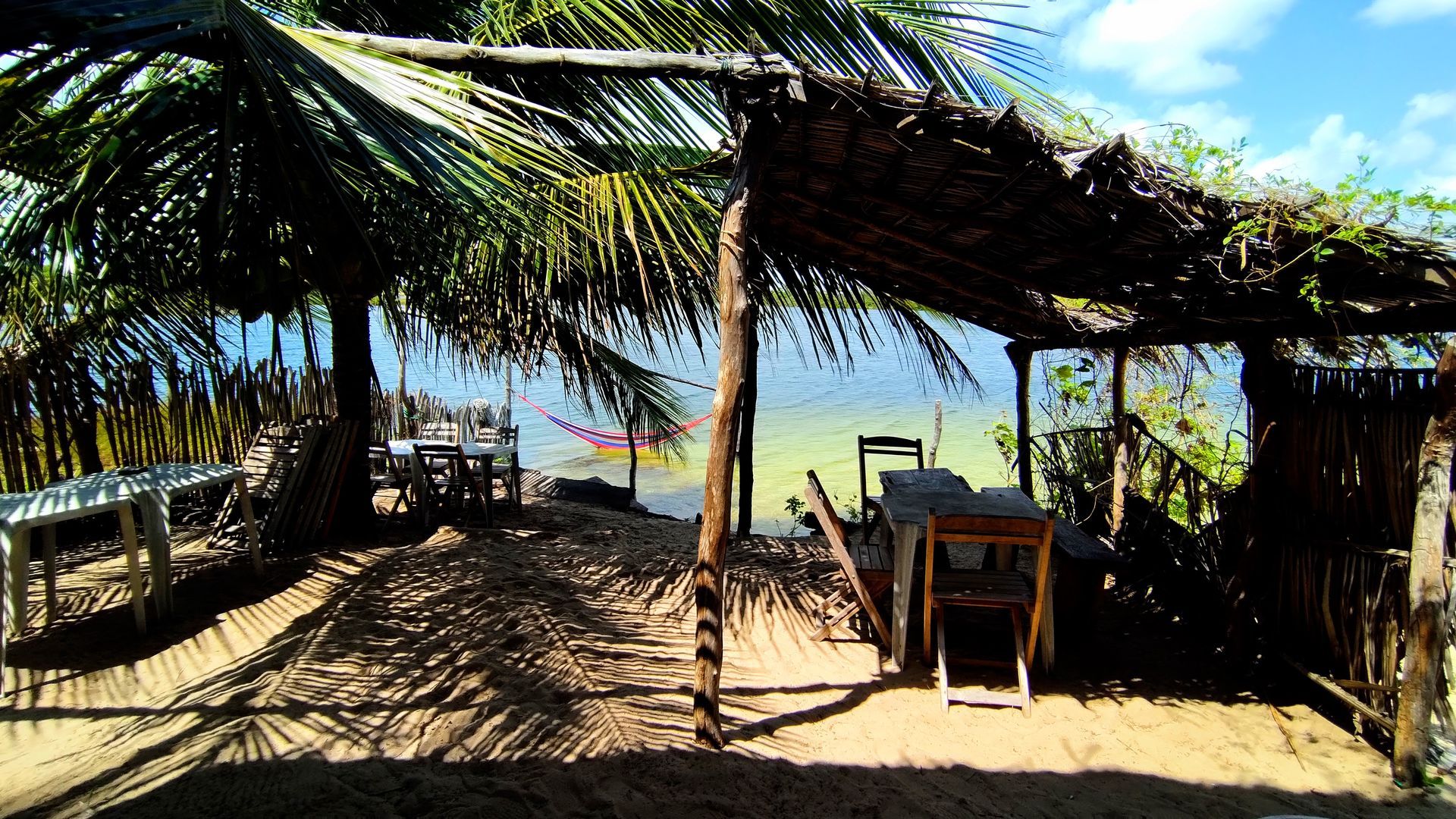Uma cabana com mesa e cadeiras debaixo de uma palmeira