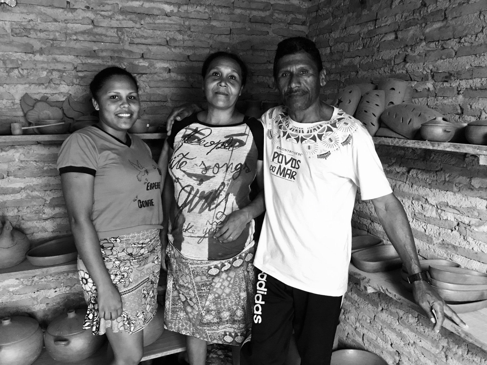 Um homem e duas mulheres posam para uma foto em uma sala cheia de potes.