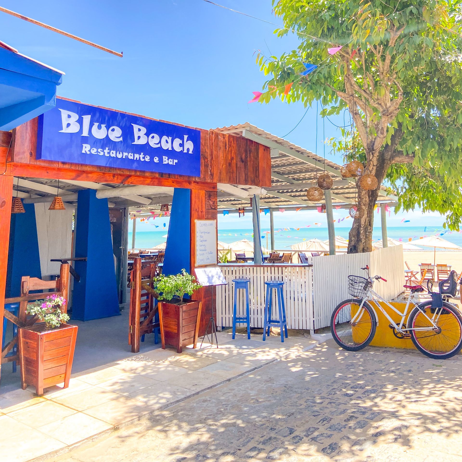 Uma bicicleta está estacionada em frente a um restaurante chamado praia azul