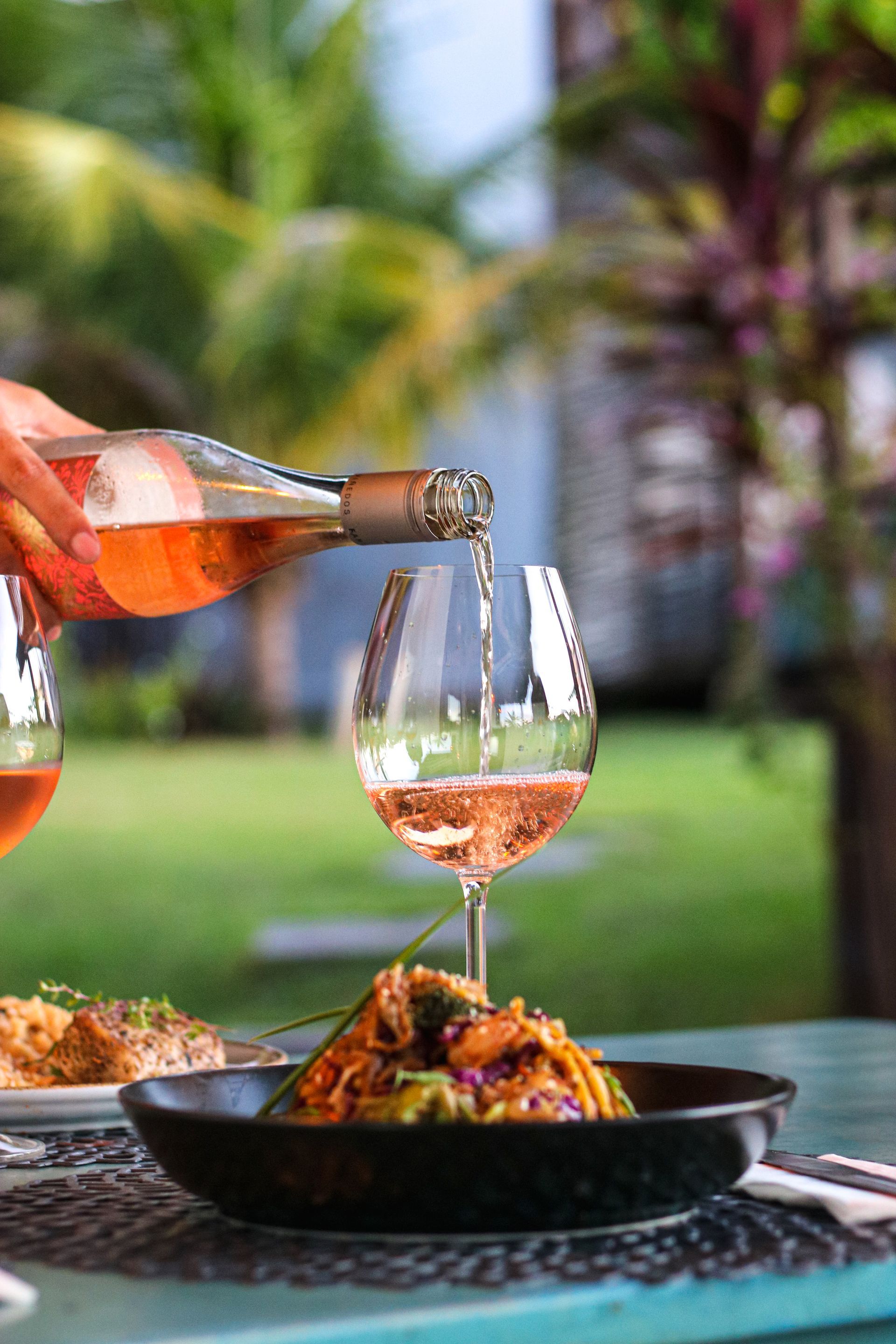 Uma pessoa está servindo vinho em um copo sobre uma mesa.