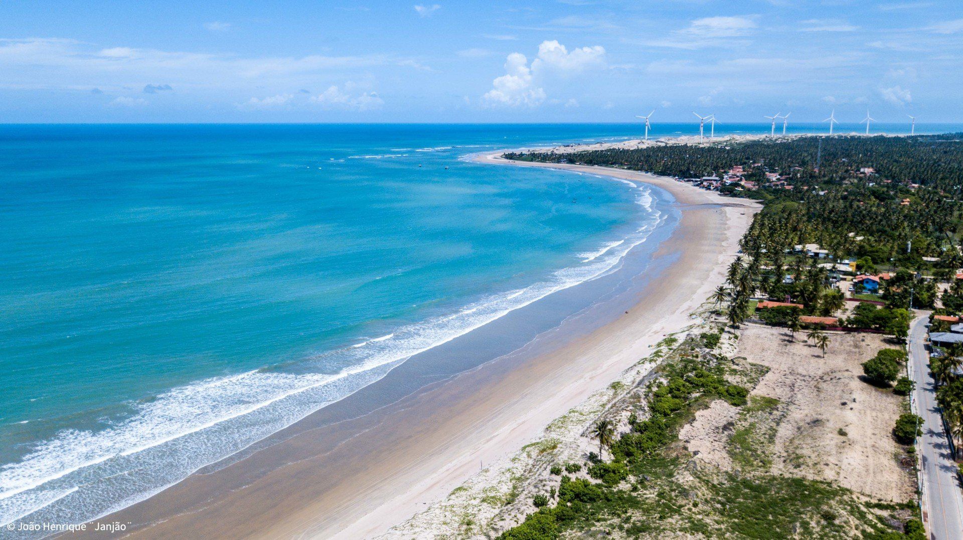 Uma vista aérea de uma praia com ondas quebrando na costa.