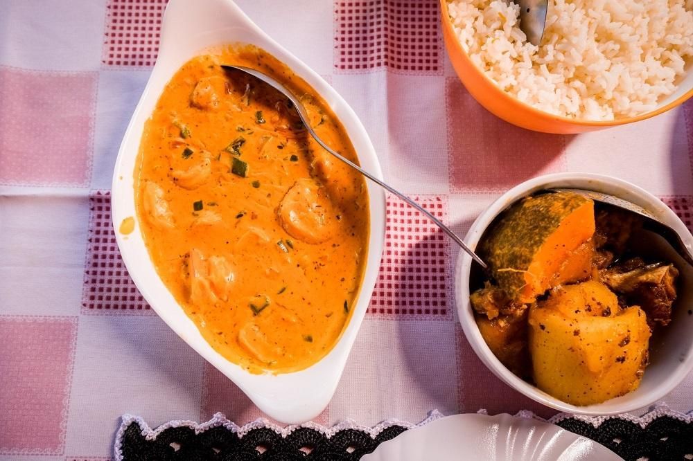 Uma tigela de curry e uma tigela de arroz estão sobre uma mesa.