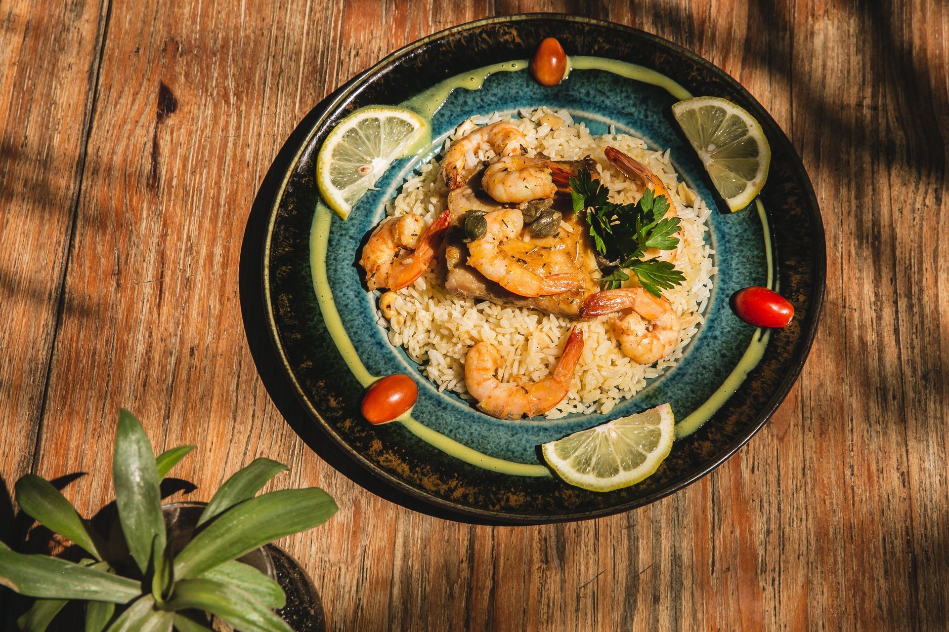 Um prato de comida com camarão e arroz em uma mesa de madeira.