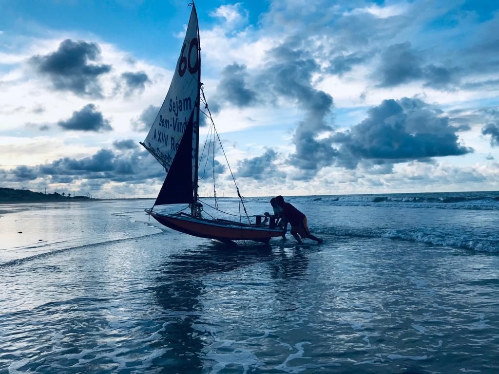 Um homem está tirando um veleiro da água em uma praia.