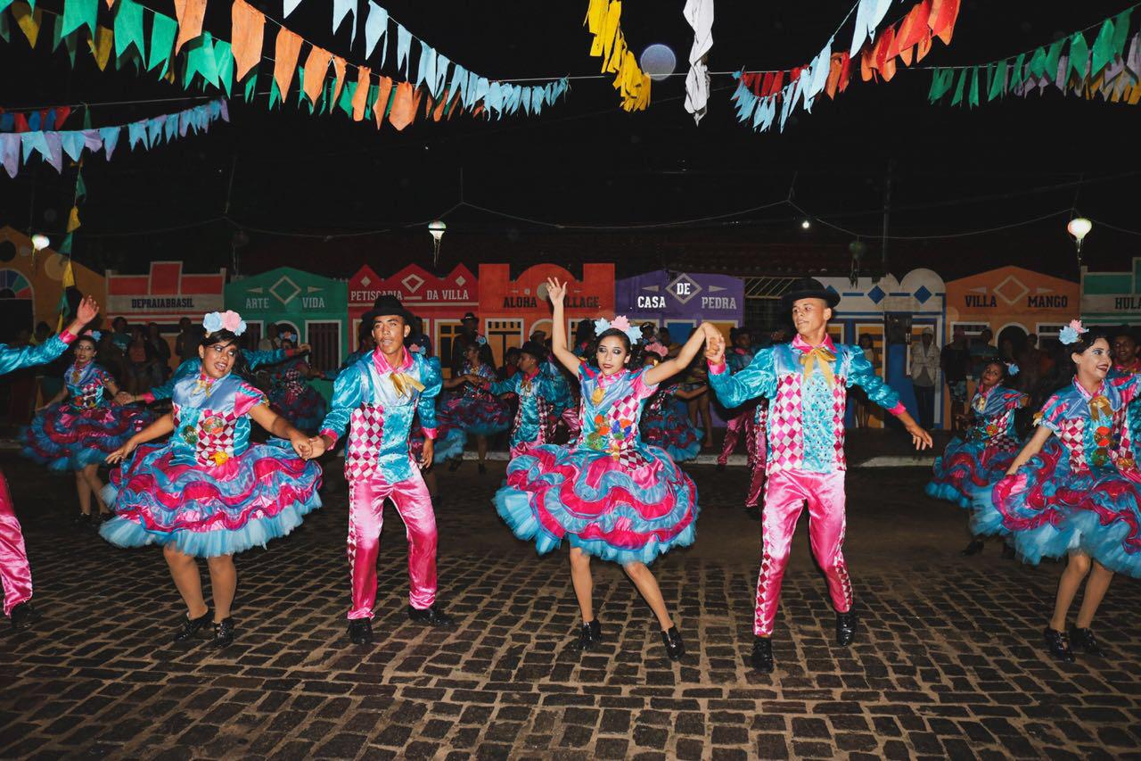 Um grupo de pessoas está dançando em uma rua de paralelepípedos.