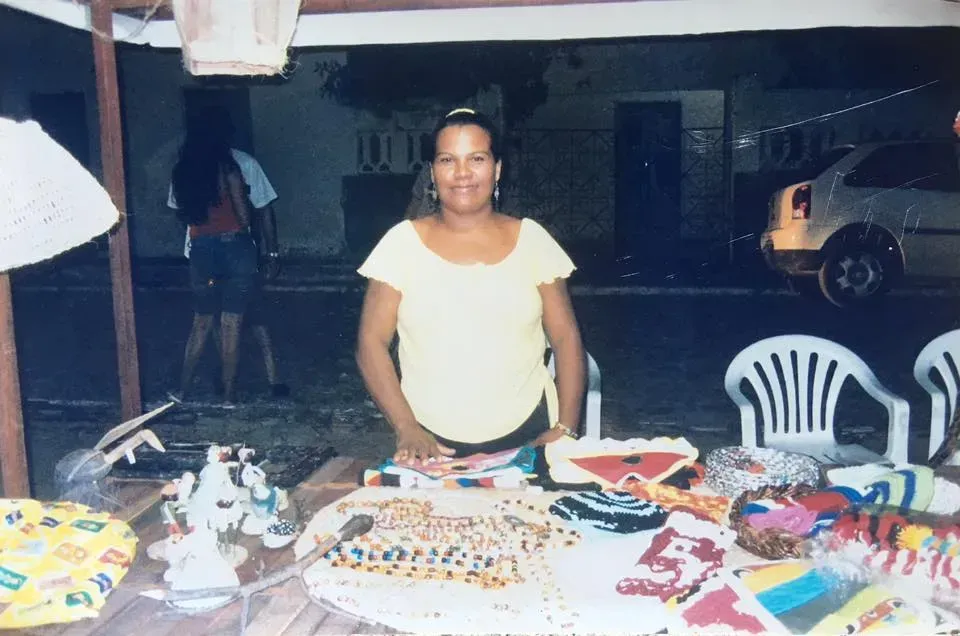 Uma mulher de camisa amarela está sentada à mesa