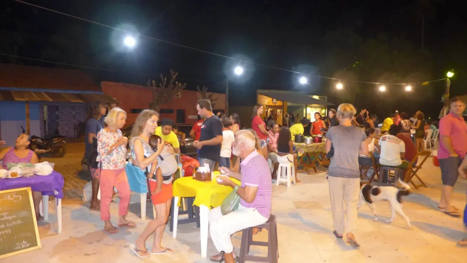 Um grupo de pessoas está em volta de mesas e mesas em uma festa.