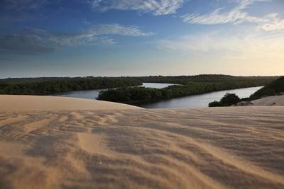 Uma vista de um rio a partir de uma duna de areia.