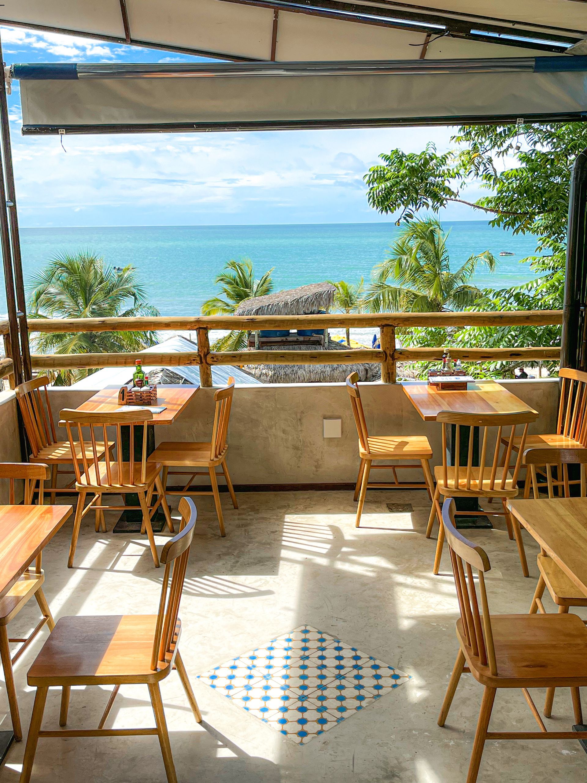 Um restaurante com mesas e cadeiras com vista para o mar.