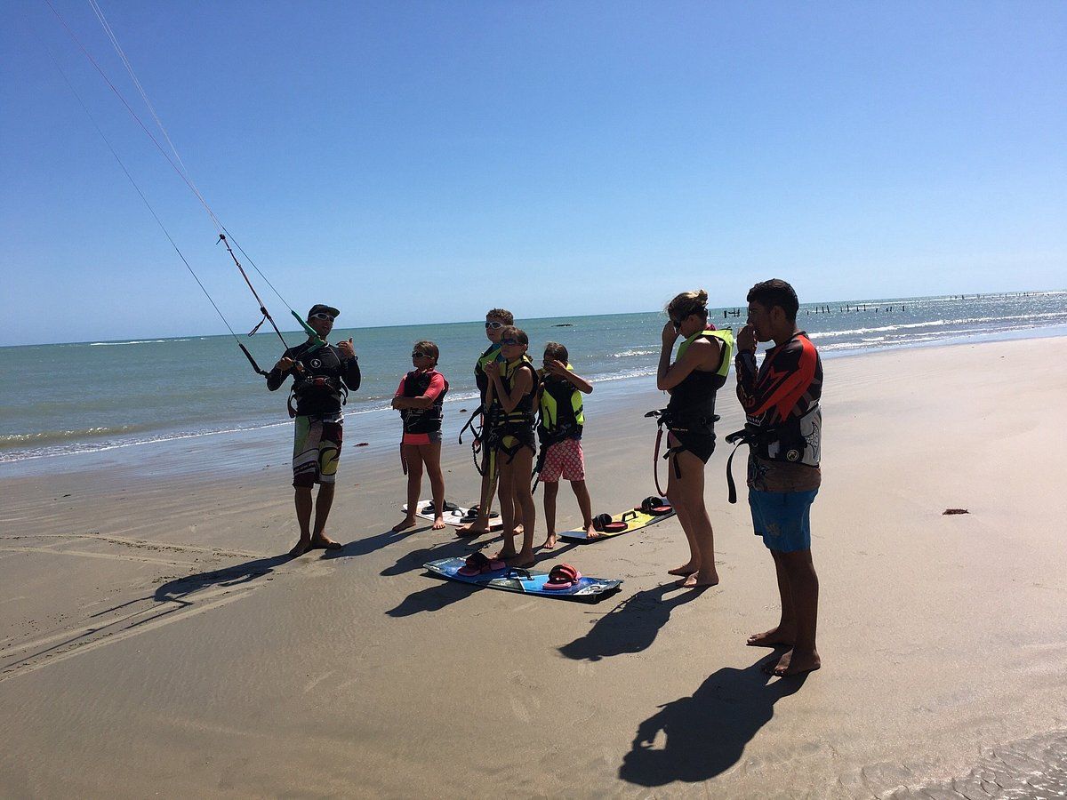 Um grupo de pessoas está em uma praia olhando para o oceano.