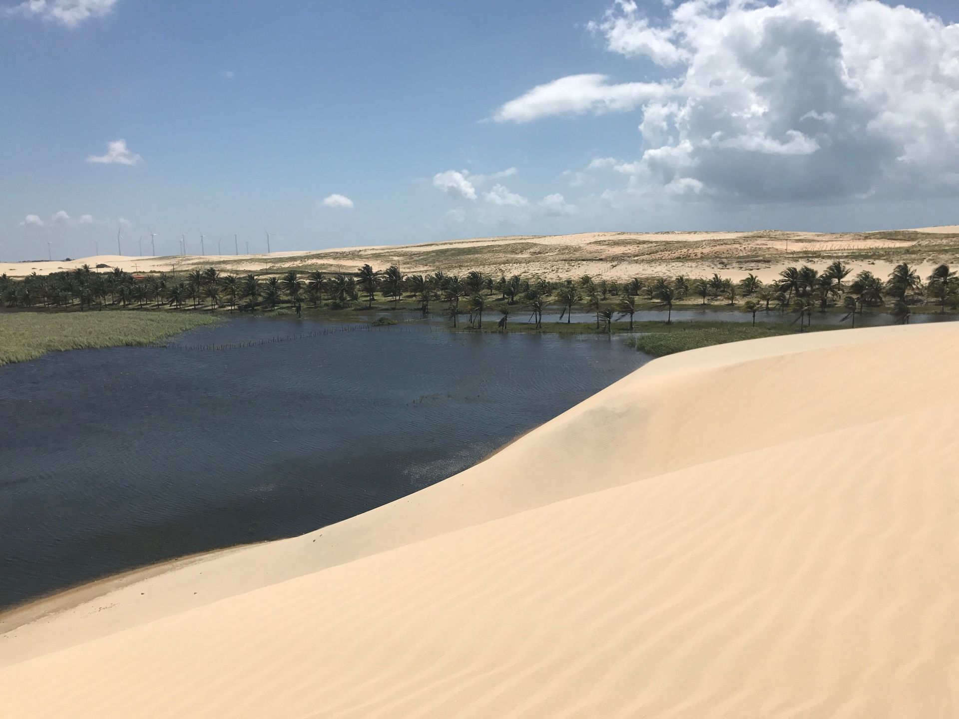 Existe um lago no meio do deserto cercado por dunas de areia.