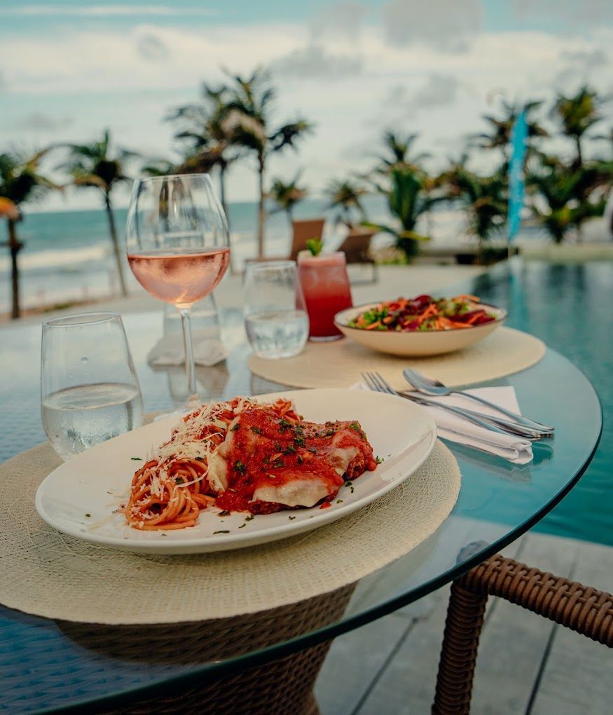Uma mesa de vidro com um prato de comida e uma taça de vinho