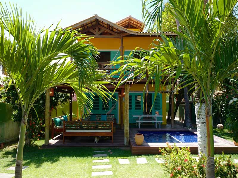 Uma casa com piscina é cercada por palmeiras