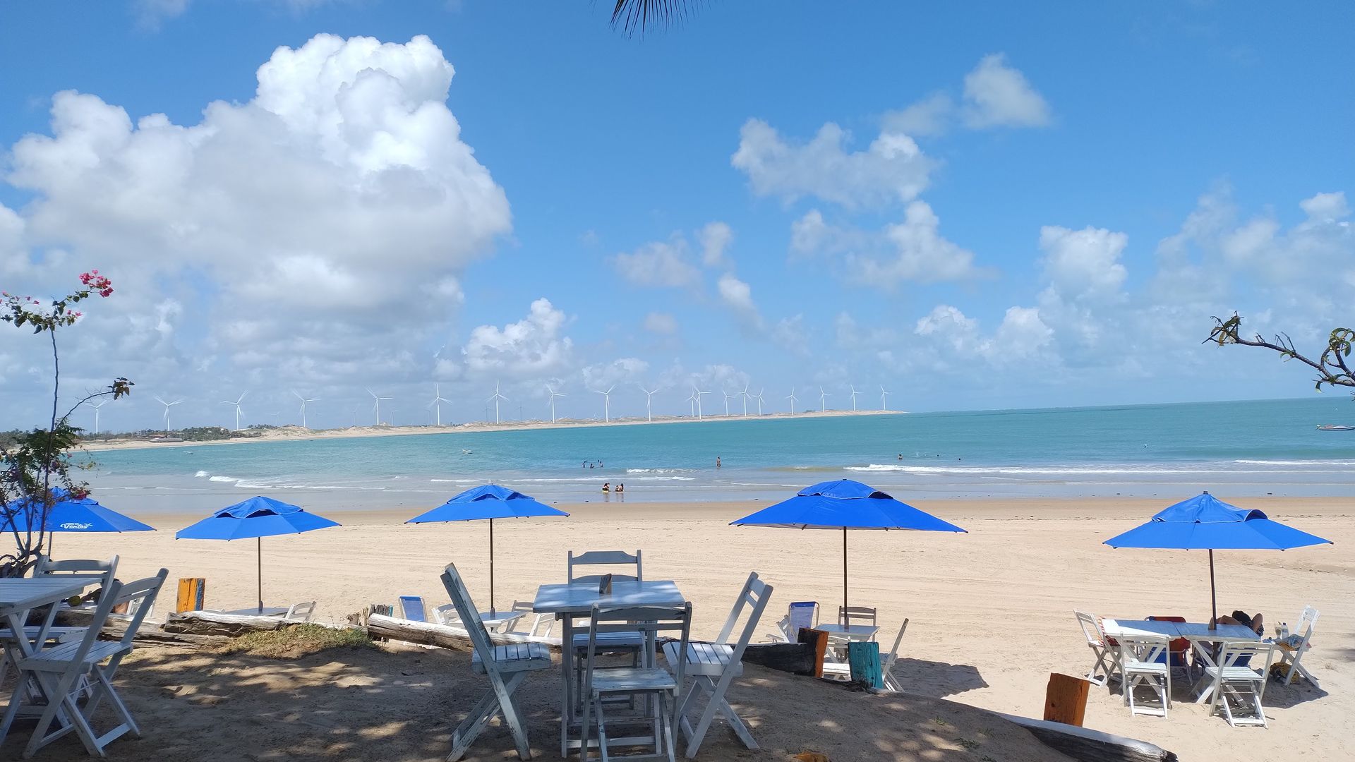 Uma praia com mesas e cadeiras e guarda-sóis azuis