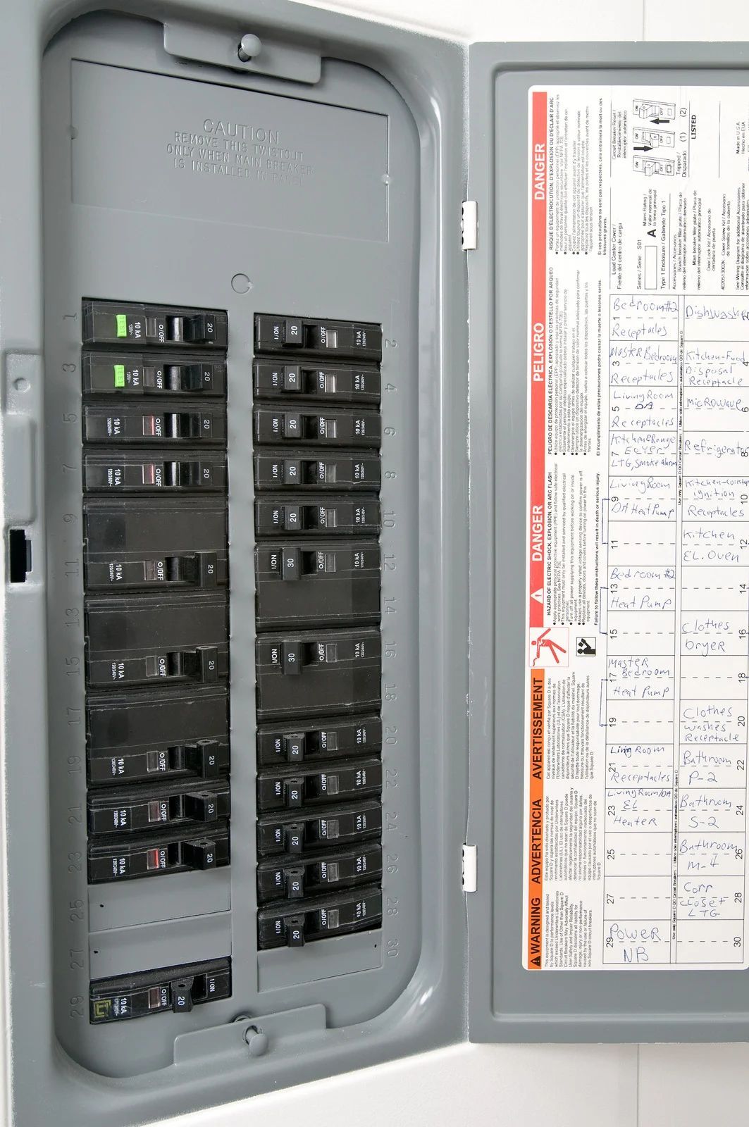 Open electrical breaker panel with labeled circuits and a diagram on the inside door.