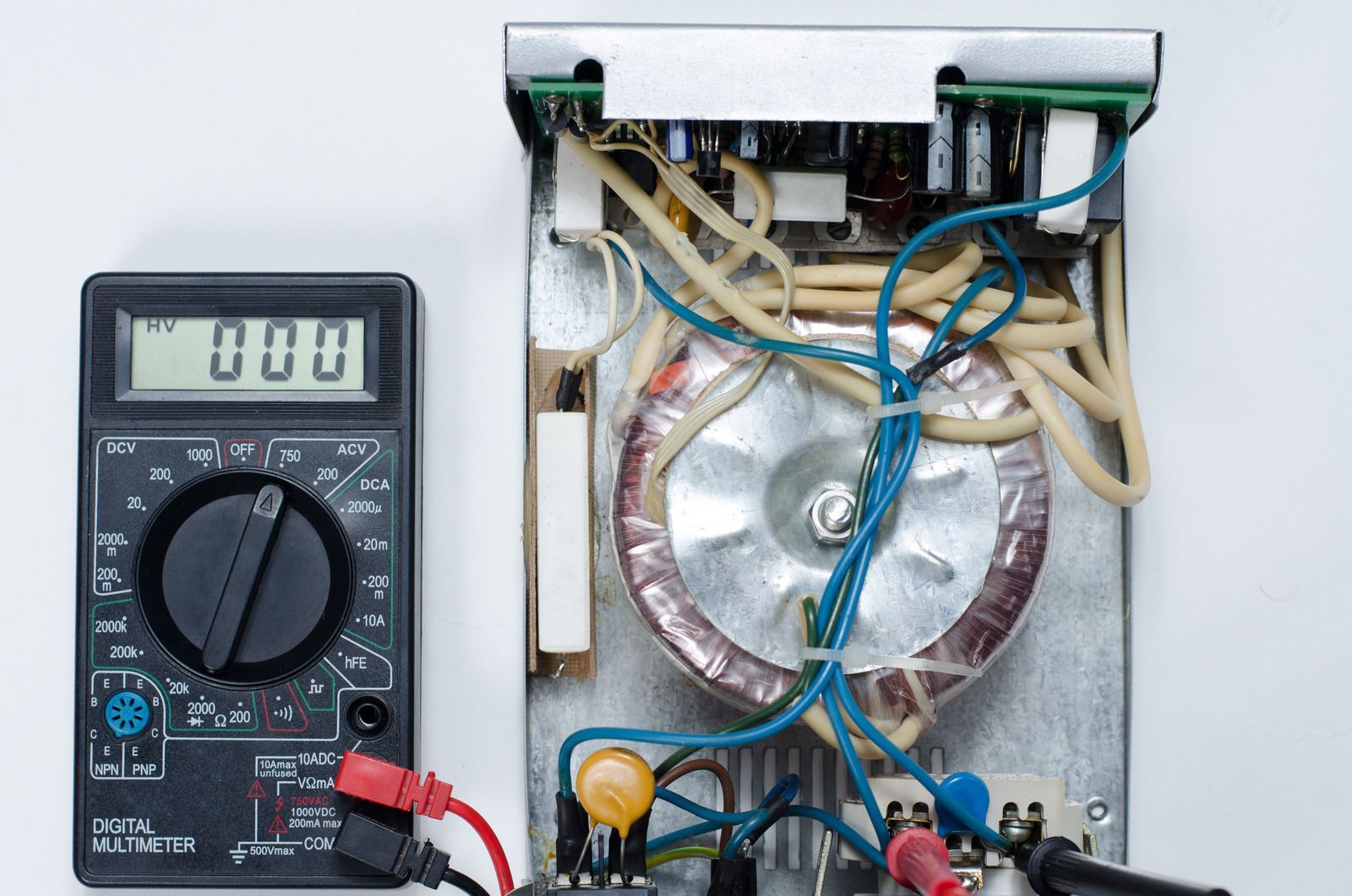 A multimeter measures the voltage of an open power supply.
