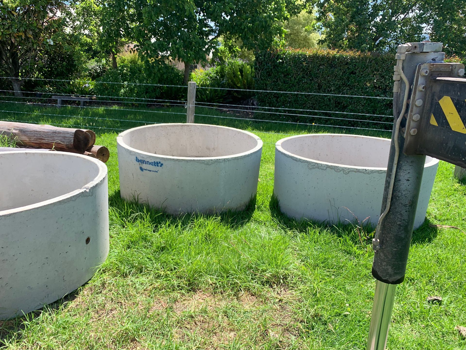 Two Empty Concrete Water Tanks Sitting On Grass — Bennett's Environmental In Wollongong, NSW
