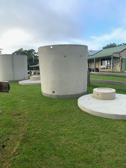A Water Tank Is Attached To The Side Of A Brick Building — Bennett's Environmental In South Nowra, NSW
